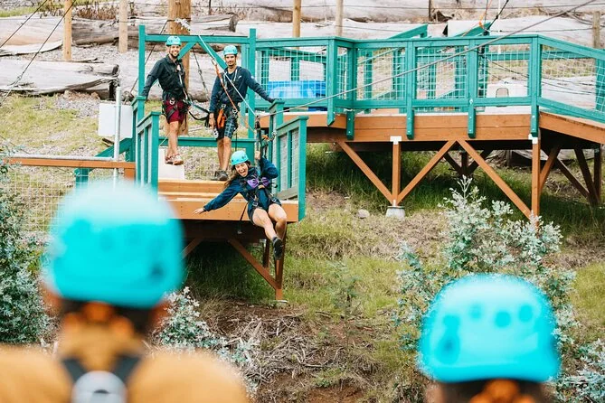 Teilnehmer mit Helmen und Klettergurten, die auf einem Pfad eines Zipline-Parcours gehen