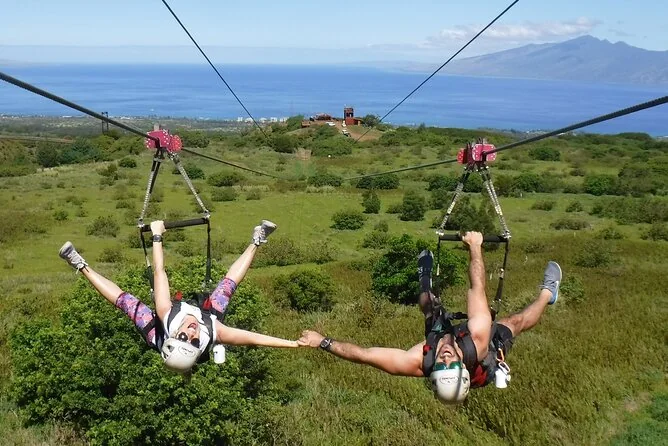 Zwei Teilnehmer nebeneinander auf Doppelbahnen über grünen Hängen in West Maui